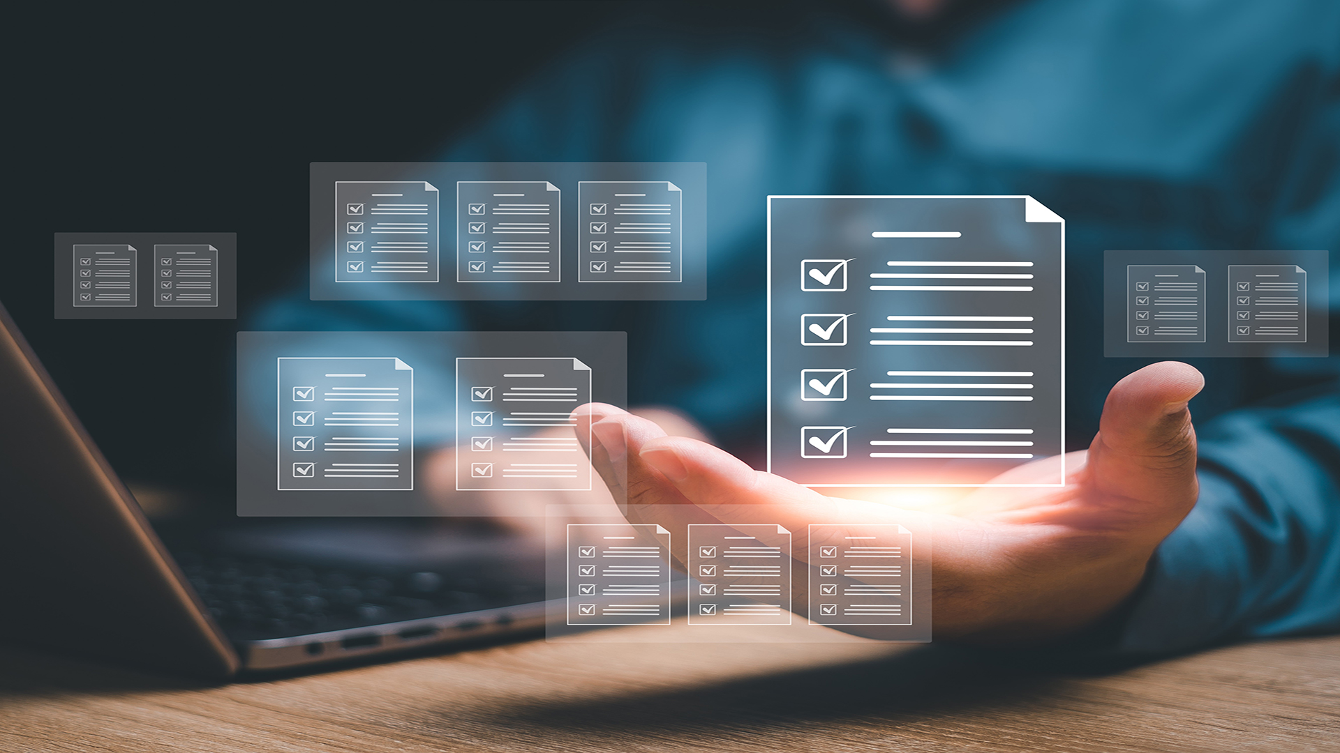 Eine Hand hält schwebende digitale Checklisten-Symbole vor einem Laptop-Hintergrund.